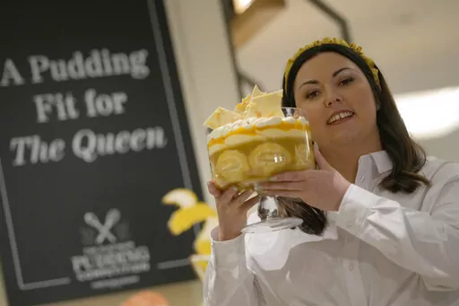 Jemma Melvin the Platinum Jubilee Pudding winner poses for the media with her creation, at a department store in London, Friday, May 13, 2022. Jemma was chosen from over 5000, entries. The 31-year-old copywriter's seven-layer lemon Swiss roll and amaretti trifle beat 5,000 desserts in a U.K.-wide competition to become the official pudding — or dessert, if you’re not British — of the Queen’s Platinum Jubilee. (AP Photo/Alastair Grant)