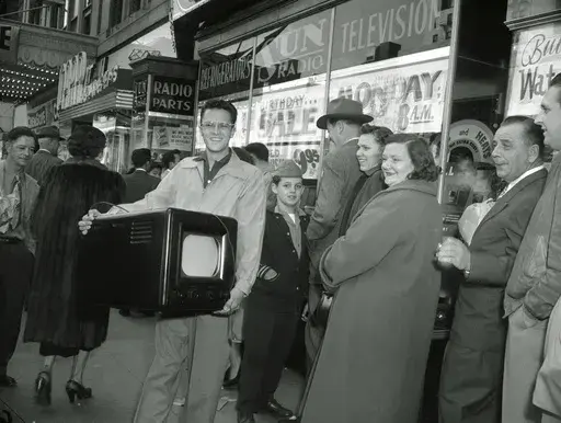Phil Bustos of Trinidad, Colo., displays the television set he bought for $29 at a Washington's Birthday sale in Washington, D.C., Feb. 22, 1954. Other bargain hunters waited to get into the packed store during the annual holiday sale. (AP Photo, File)